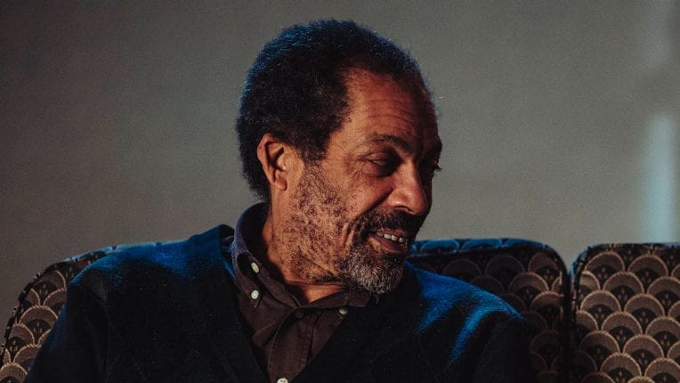 Ben Onwukwe in a maroon shirt and blue jumper.